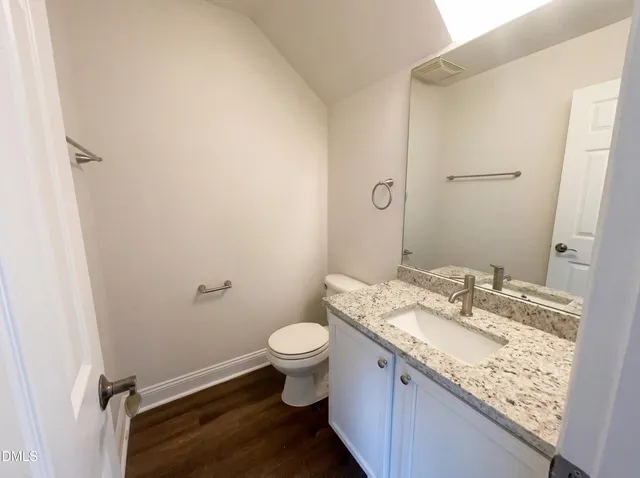 a bathroom with a granite countertop sink toilet and mirror