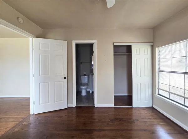 an empty room with wooden floor & windows and bathroom