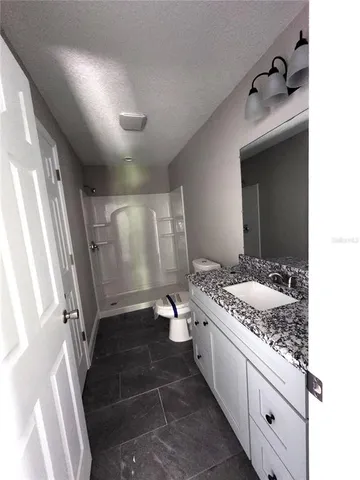 a bathroom with a granite countertop sink a toilet and shower