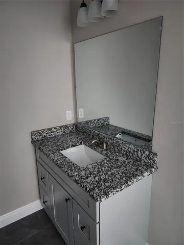 a bathroom with a granite countertop sink and white cabinets