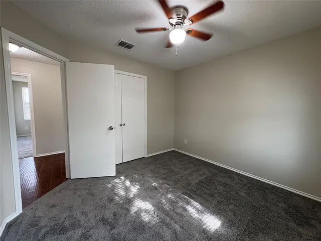 an empty room with closet and a ceiling fan