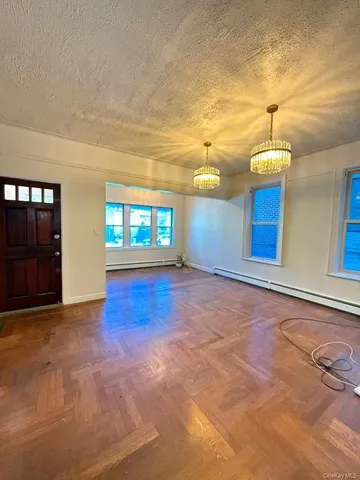 a view of an empty room with window and wooden floor