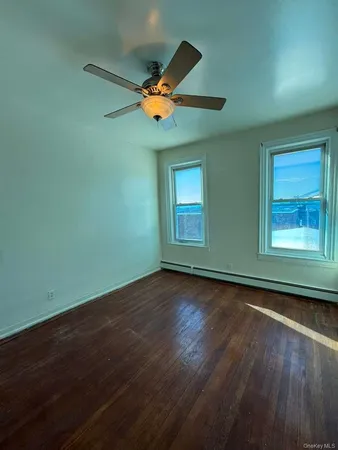 an empty room with wooden floor fan and windows