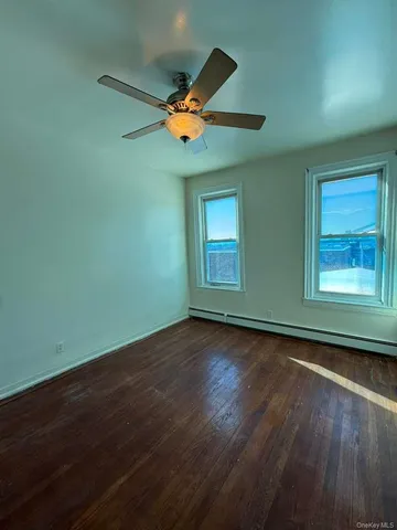 an empty room with wooden floor fan and windows
