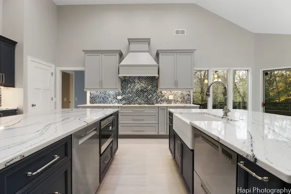 a room with stainless steel appliances kitchen island granite countertop a sink and cabinets