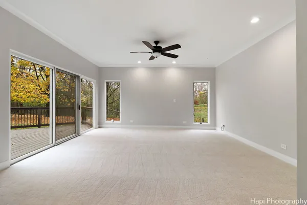 an empty room with chandelier fan and windows