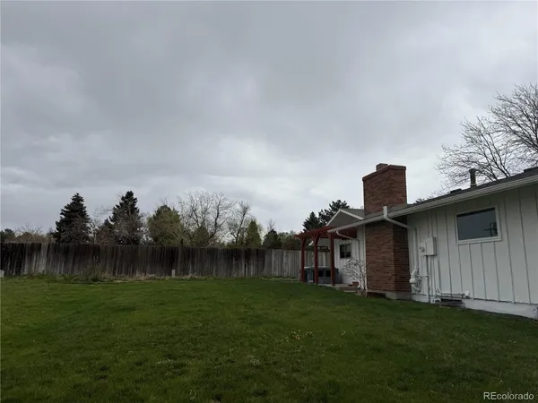 a view of a back yard of the house with green space and wooden fence