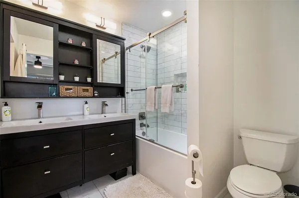 a bathroom with a toilet sink double vanity and mirror