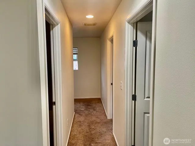 a view of a hallway with wooden floor and a bathroom