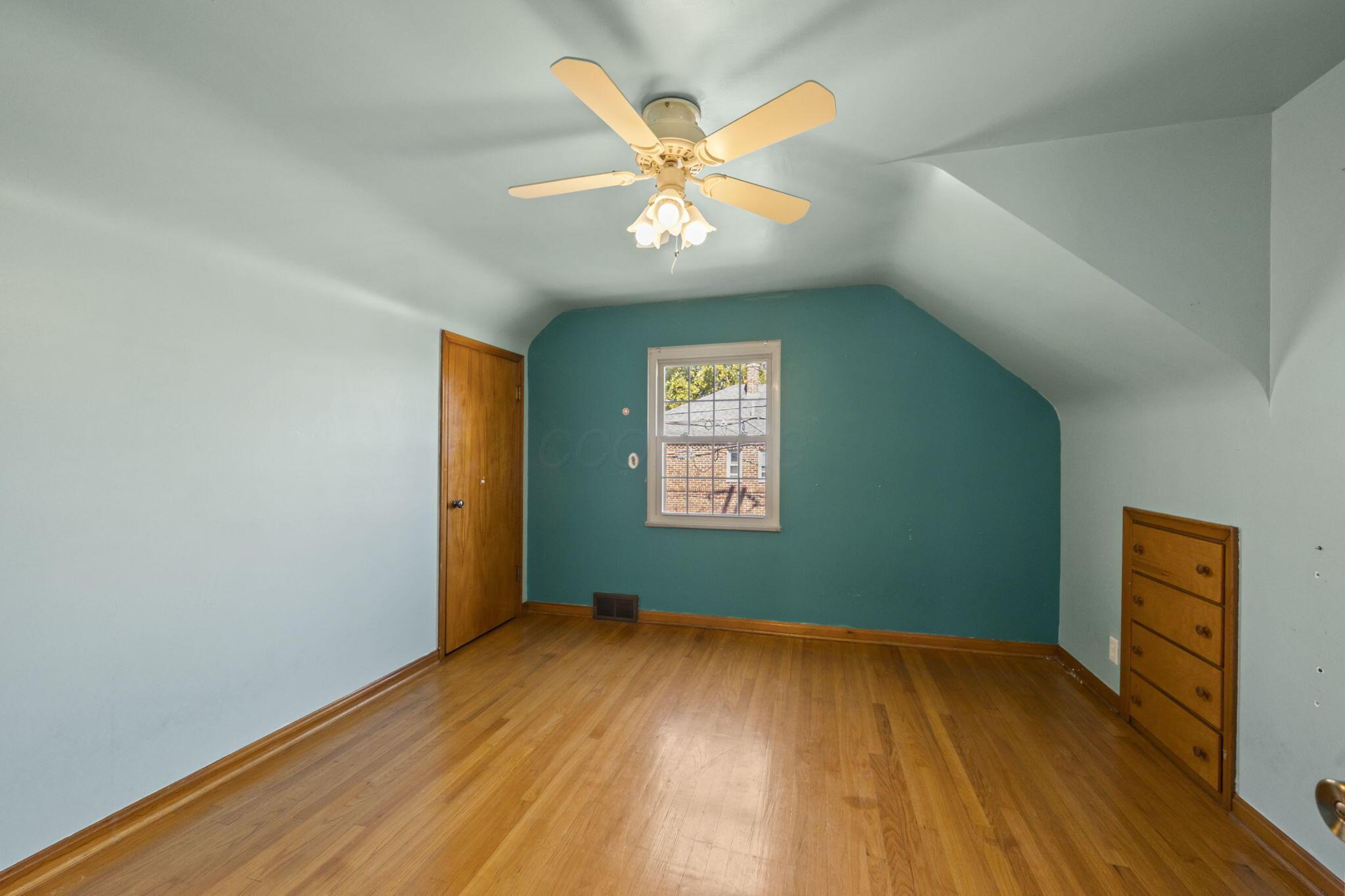 40 South Kellner Road Columbus, OH 43209 - Photo 25 of 57 Spacious attic bedroom with sloped ceilings, warm wood-finish flooring, and a teal accent wall