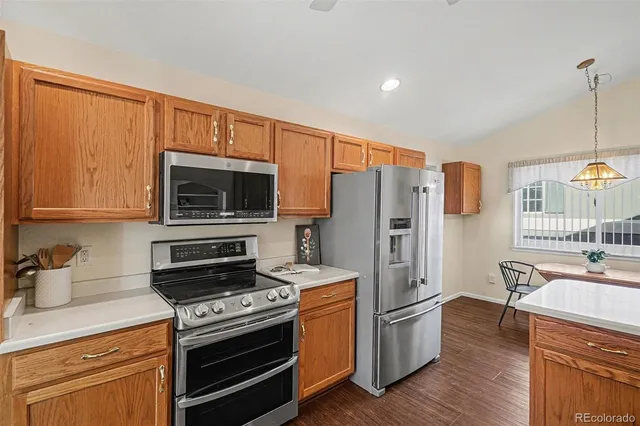 a kitchen with stainless steel appliances a stove a refrigerator a sink a oven with wooden floor and cabinets