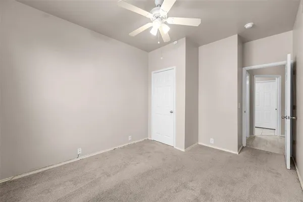 an empty room with closet and a chandelier fan