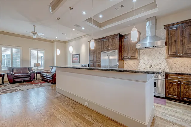 a large kitchen with stainless steel appliances a large counter top a stove and a wooden floors