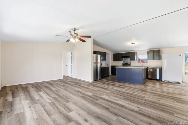a view of a kitchen with a sink a refrigerator a ceiling fan and wooden floor