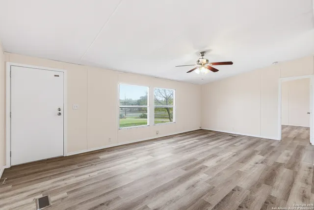 a view of an empty room with wooden floor and a window