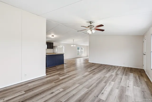 an empty room with wooden floor and a ceiling fan