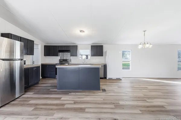 a view of kitchen with stainless steel appliances granite countertop a stove a sink dishwasher a refrigerator and a refrigerator with wooden floor