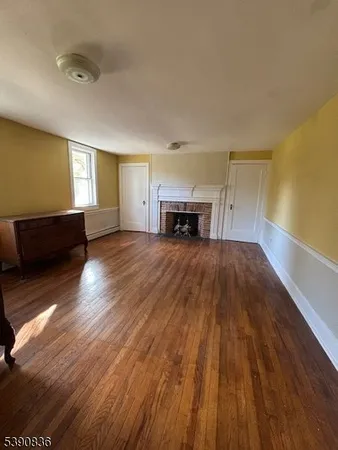 a view of empty room with wooden floor and fireplace