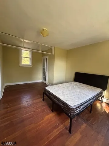 an empty room with wooden floor chandelier fan and windows