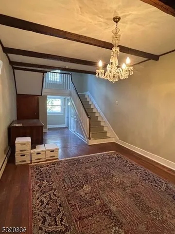 a view of a hallway with wooden floor and chandelier