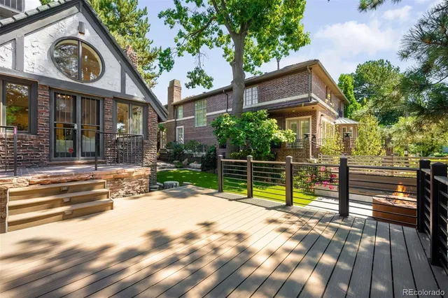 a backyard of a house with table and chairs plants and large trees