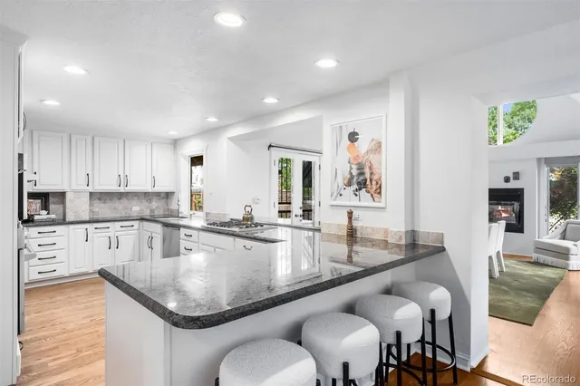 a kitchen with stainless steel appliances granite countertop a table chairs sink and cabinets