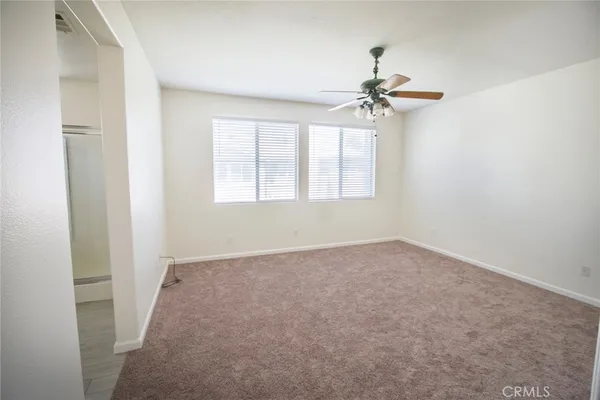an empty room with windows and fan