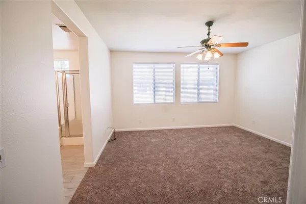 an empty room with windows and fan