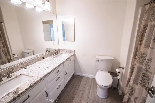 a bathroom with a granite countertop toilet sink and mirror