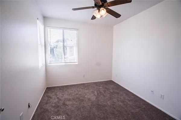 an empty room with a window and a fan