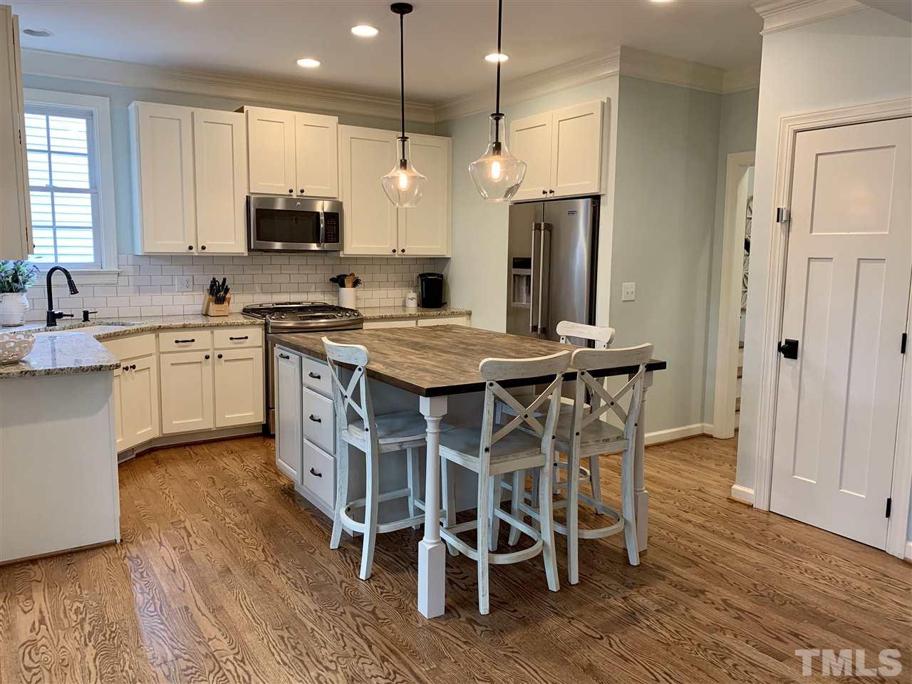 606 Scotts Ridge Trail Apex, NC 27502 - Photo 8 of 22 a kitchen with stainless steel appliances granite countertop a table chairs sink refrigerator and microwave