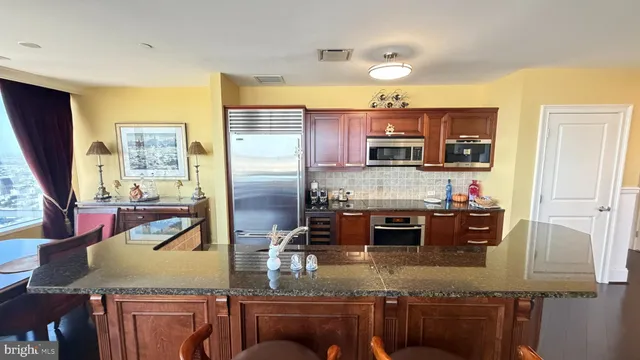 a kitchen with kitchen island granite countertop a stove top oven microwave and refrigerator