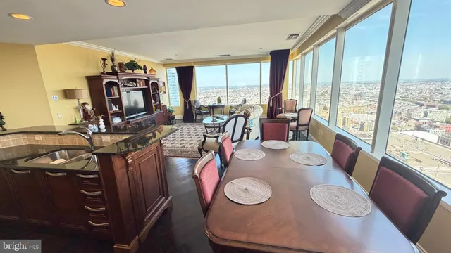 a view of a dining room with furniture a chandelier and large windows