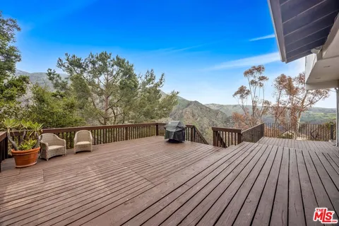 a view of a roof deck with table and chairs couches with wooden floor