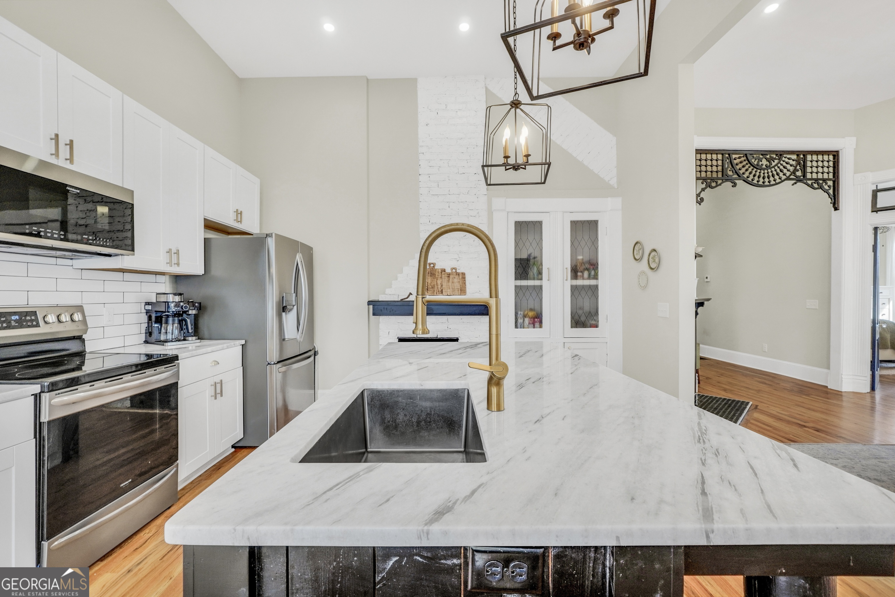 263 Julia Street Monticello, GA 31064 - Photo 11 of 48 a kitchen with stainless steel appliances granite countertop a refrigerator a stove and a sink with wooden floor