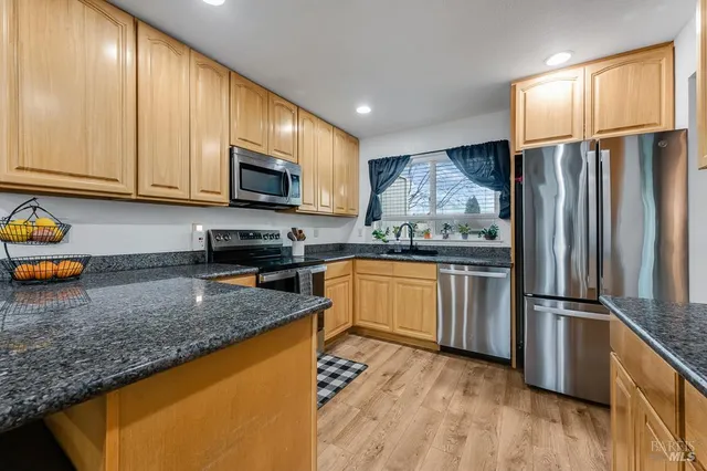 a kitchen with granite countertop stainless steel appliances a refrigerator stove microwave and sink