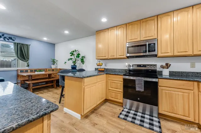 a kitchen with stainless steel appliances granite countertop a stove top oven a sink dishwasher and cabinets with wooden floor