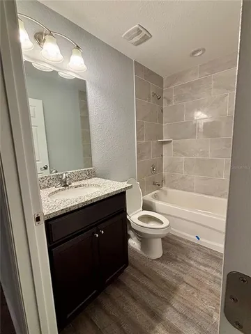 a bathroom with a granite countertop toilet a sink and a bathtub