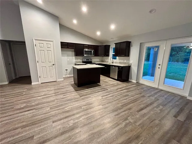 a large white kitchen with wooden floors and stainless steel appliances