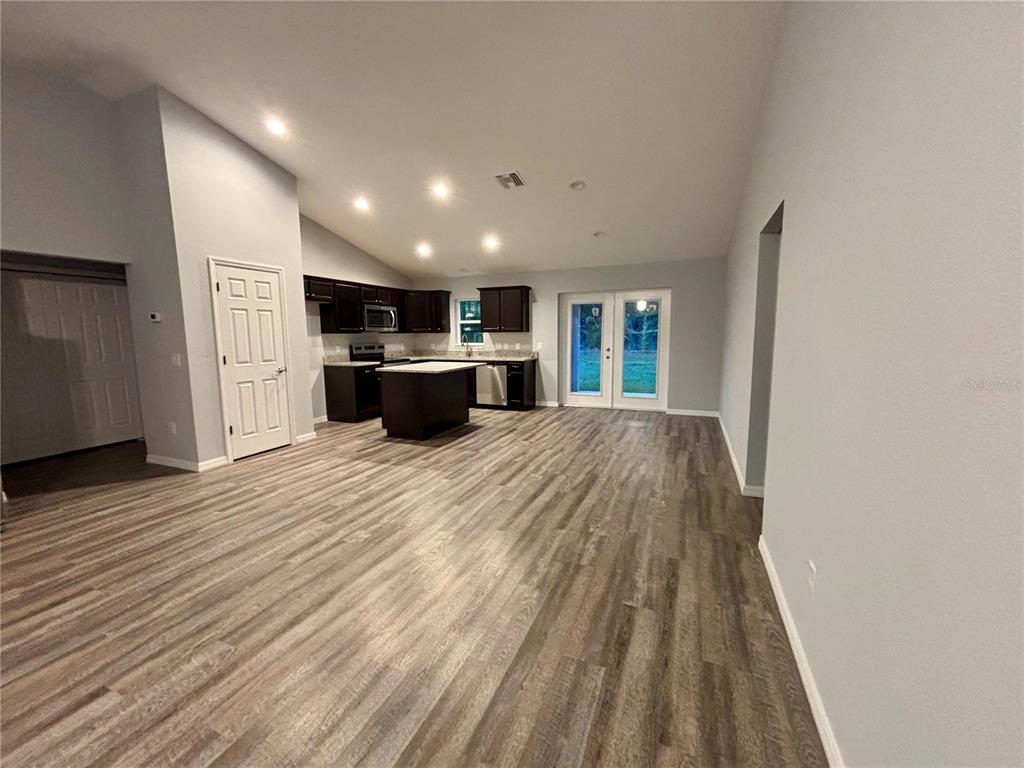 12472 Southeast 67th Terrace Road Belleview, FL 34420 - Photo 5 of 18 a open kitchen with kitchen island a sink dishwasher stove with wooden floor and chandelier