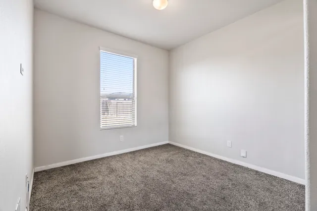 a view of an empty room with wooden floor and a ceiling fan