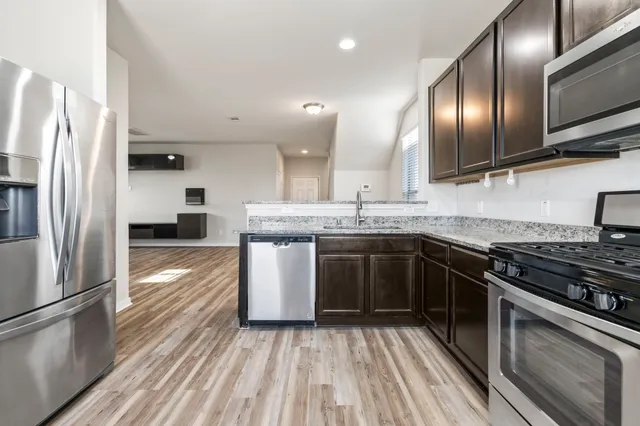a kitchen with stainless steel appliances granite countertop a sink a stove and a refrigerator