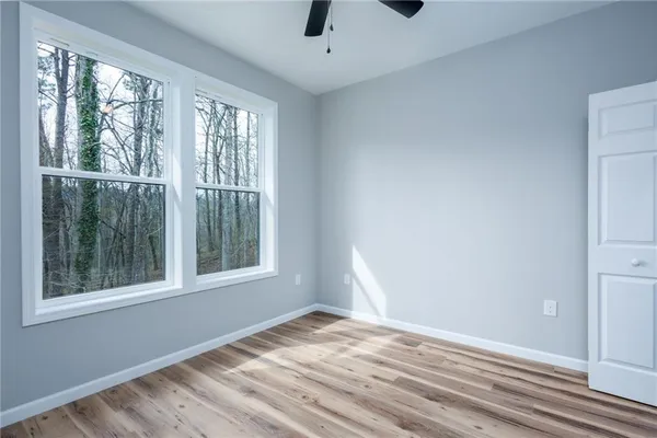a view of an empty room with wooden floor and windows