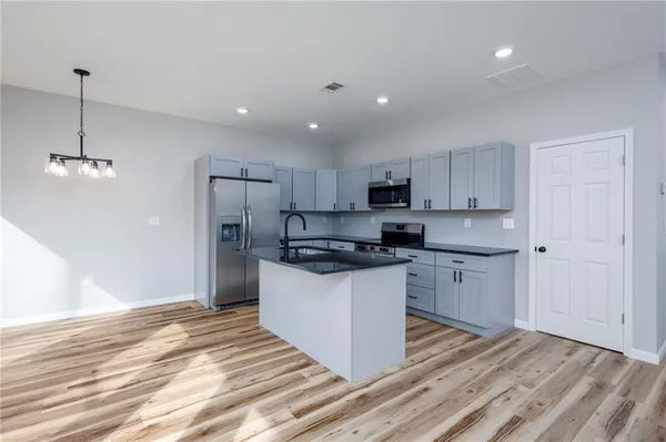 a kitchen with stainless steel appliances granite countertop a sink a stove a refrigerator and white cabinets