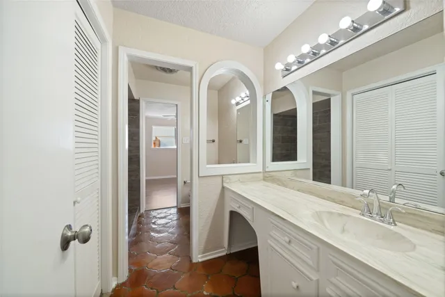 a spacious bathroom with a granite countertop sink a mirror and shower