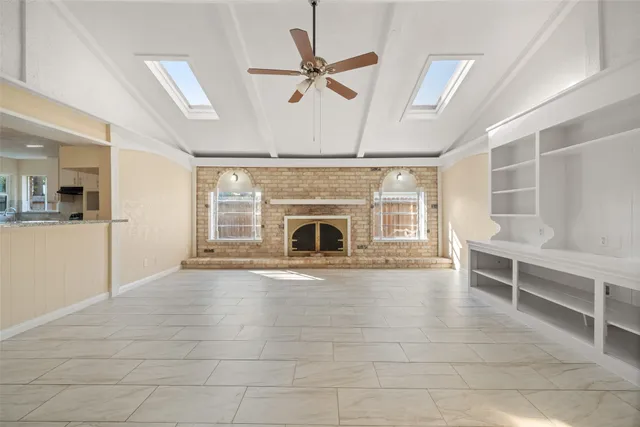 a view of an empty room with a fireplace and a ceiling fan