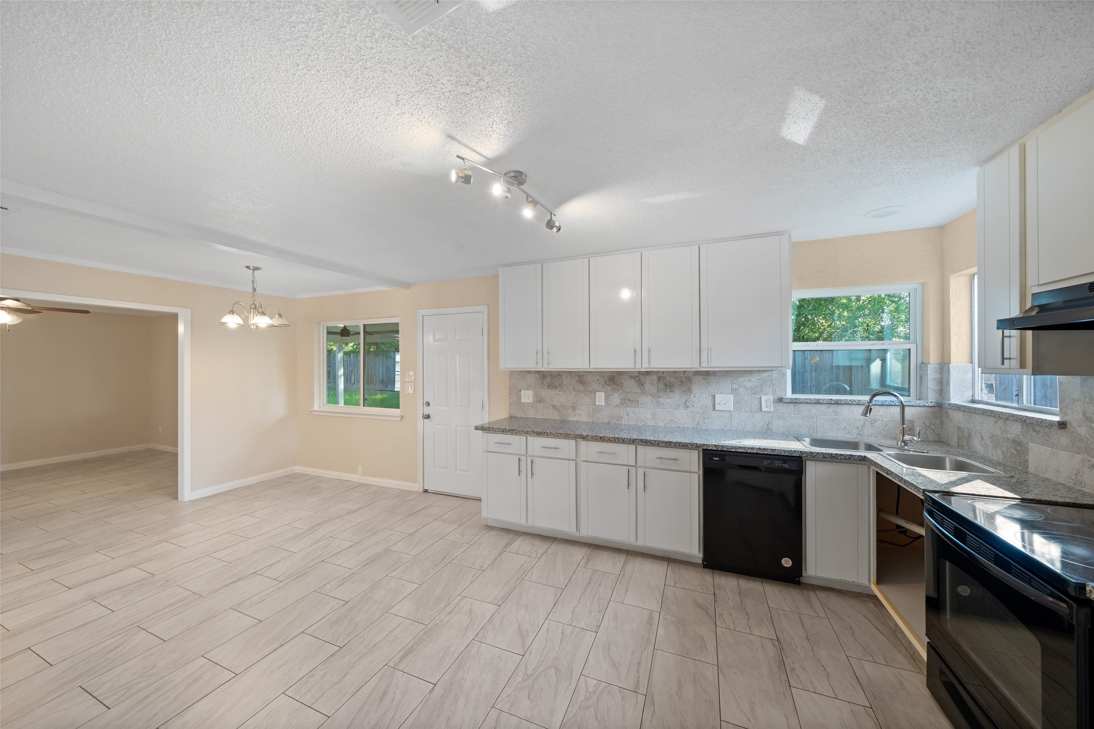 19218 Enchanted Oaks Drive Spring, TX 77388 - Photo 6 of 20 a large kitchen with granite countertop a stove top oven a sink dishwasher and white cabinets with wooden floor