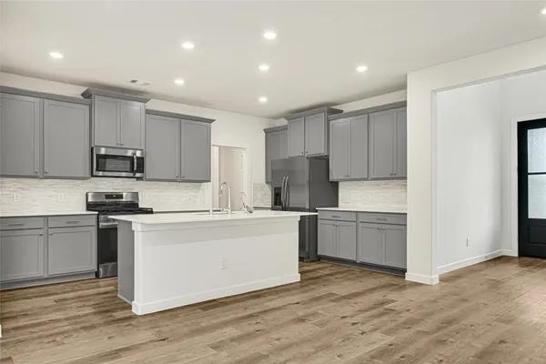 a kitchen with stainless steel appliances granite countertop a stove top oven a sink and a refrigerator