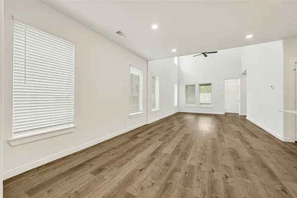 a view of empty room with wooden floor and fan