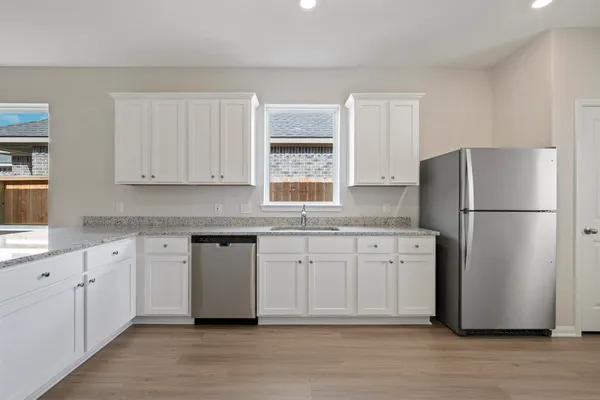 a kitchen with stainless steel appliances granite countertop a refrigerator sink and white cabinets